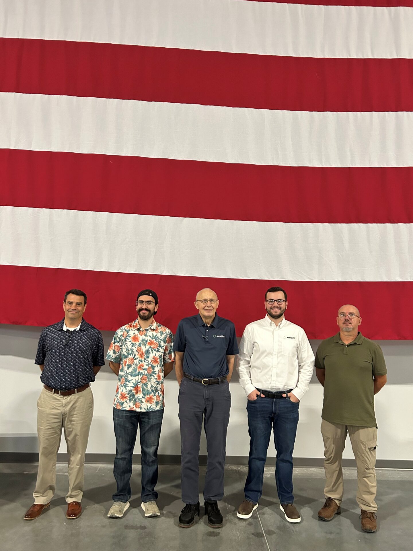 five men standing in front of a large American flag